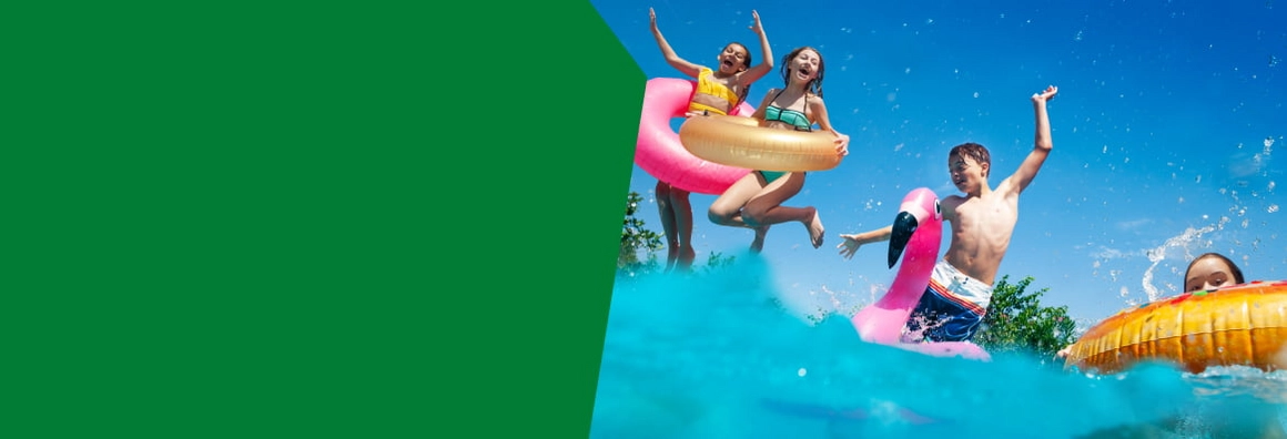 Fröhliche Kinder springen mit aufblasbaren Tieren in einen Pool.